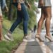 Grupa ljudi hoda po različitim podlogama — travi i asfaltu — noseći različite tipove obuće: bosi, u patikama, štiklama i sandalama.