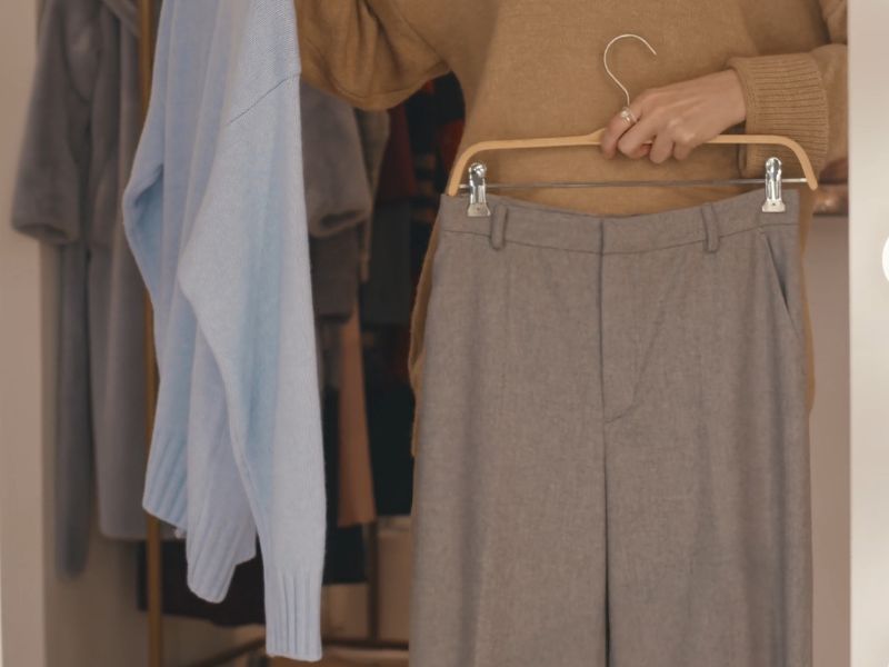 Devojka bira pantalone i džempere u prodavnici