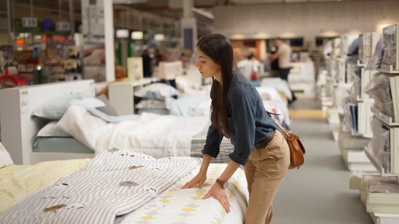 Žena proverava tvrdoću izloženog dušeka u salonu