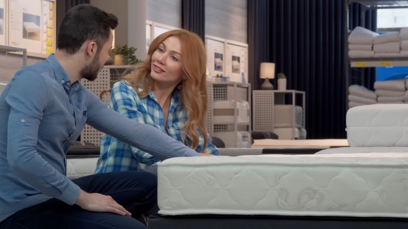 Par razgleda dušeke u prodavnici nameštaja i proverava tvrdoću rukom pre kupovine