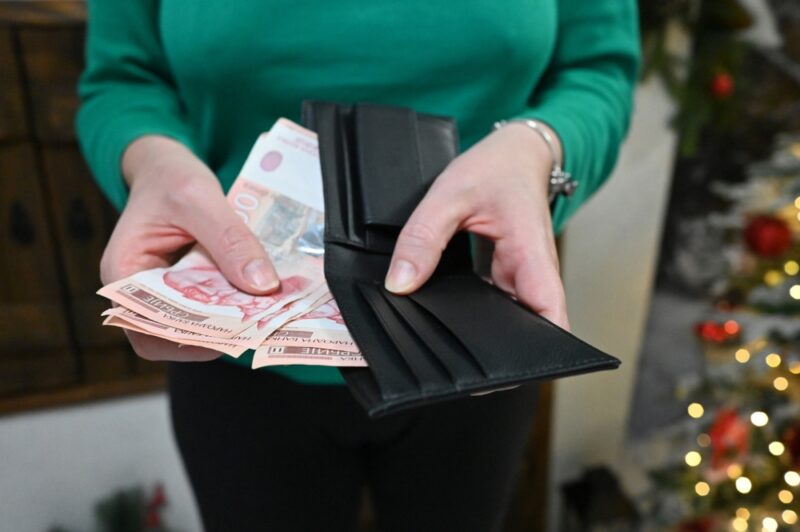 Osoba drži novac i novčanik u rukama